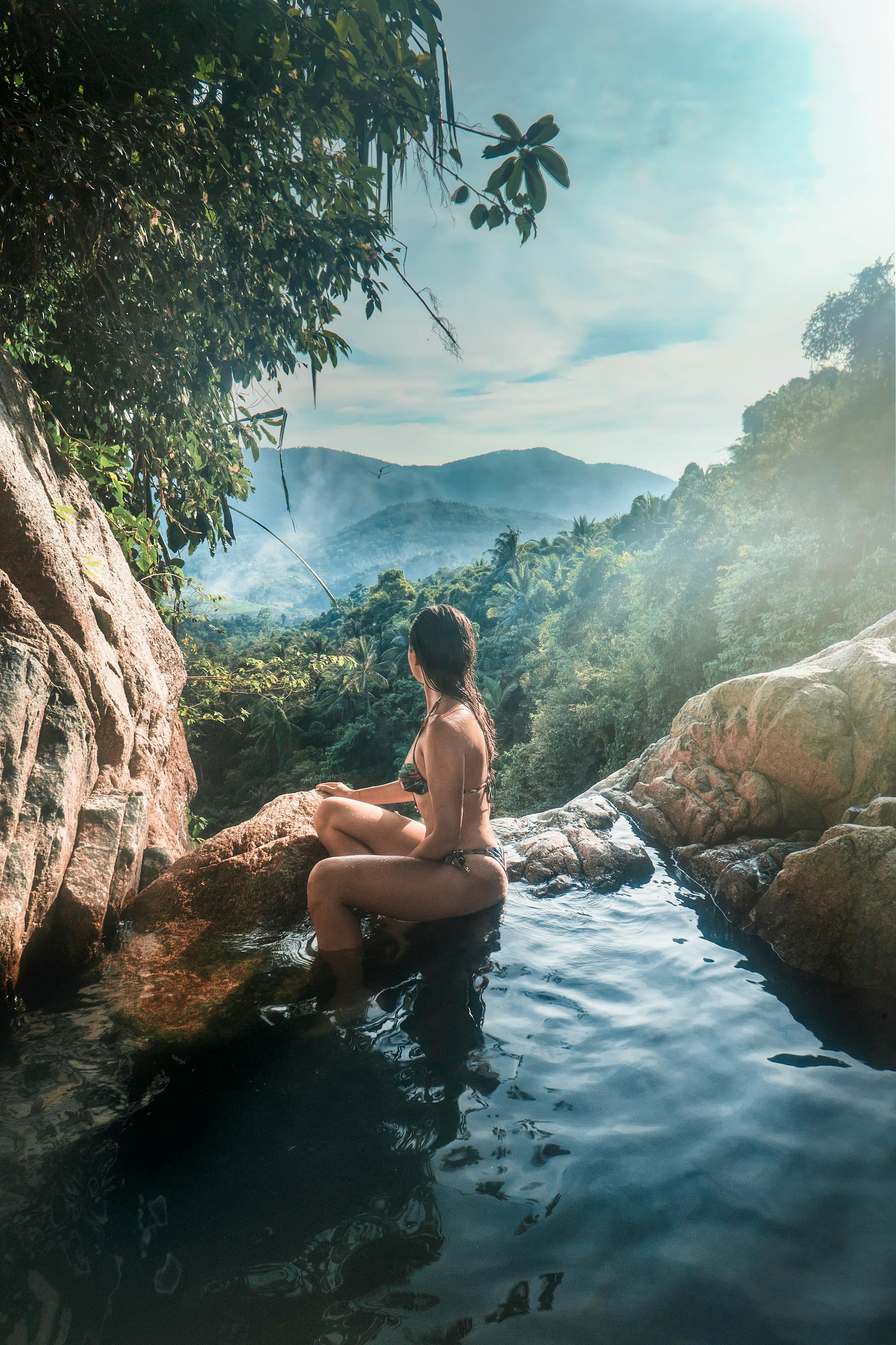 woman sitting at the edge of pool overlooking mountain